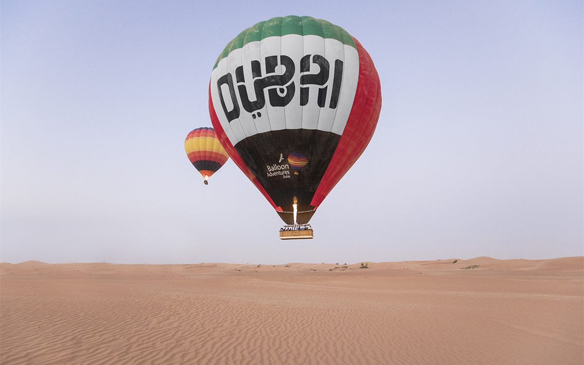 Hot air balloon floating above the desert at sunrise