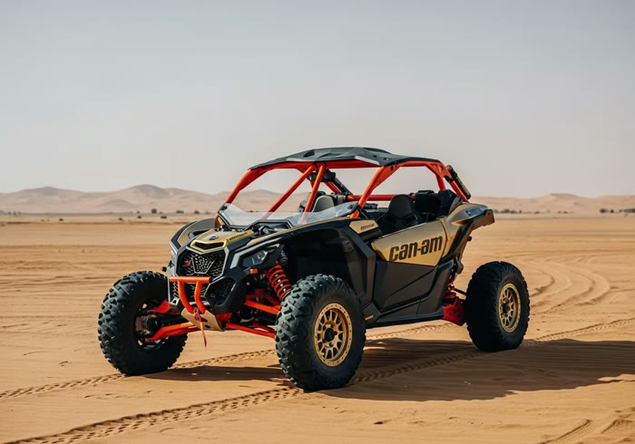 Gold Can-Am Maverick X3 buggy on a Dubai red dune